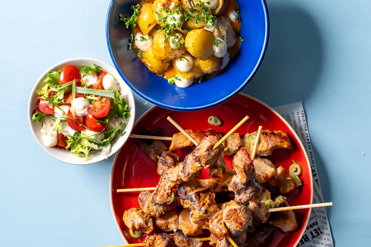 Petites brochettes de porc, salade et patatas bravas